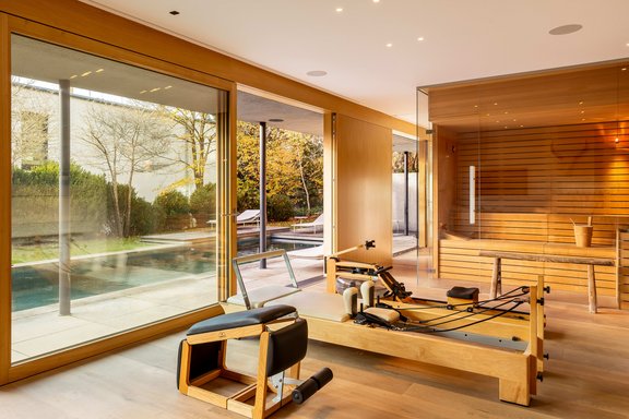 Zweites Wohnzimmer vor dem Pool als Fitnessbereich mit Sauna und Kamin