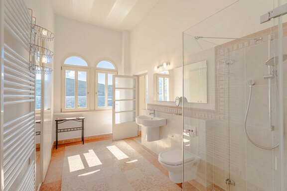 A bathroom bathed in natural light with a view of Lake Garda