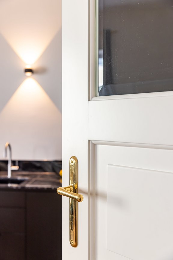 Extrahohe weiße Kassettentüren mit Messingbeschlägen