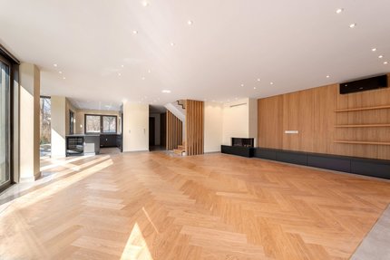 Edles Fischgrätparkett, ein Panoramakamin und große Fensterfronten