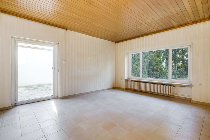 Das geräumige Wohnzimmer öffnet sich zu einer geschützten Terrasse mit Gartenblick