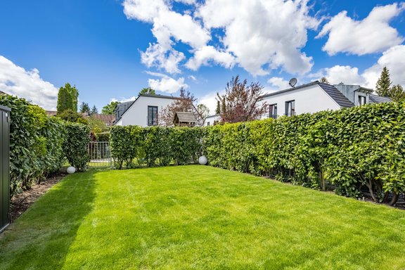 Hinter dem Haus erstreckt sich ein sonniger Garten