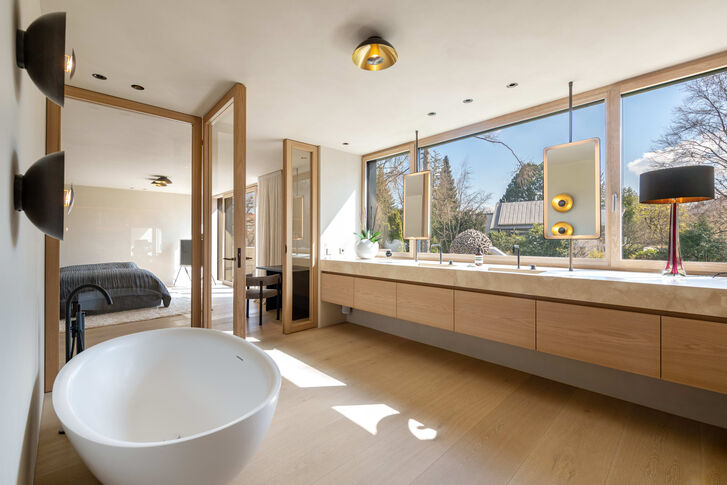 Luxuriöses, lichtdurchflutetes Badezimmer mit Einbauten und freistehender Wanne