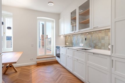 Weiße Schreinerküche mit Essecke und Zugang zur Terrasse