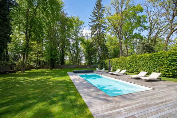 A 10-meter-long pool with a deck for relaxing in a park-like setting