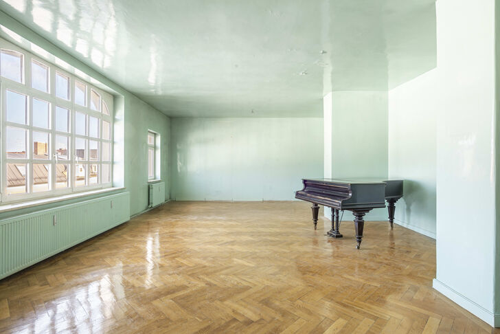 Fischgrätparkett und das beeindruckende Atelierfenster prägen das Wohnzimmer
