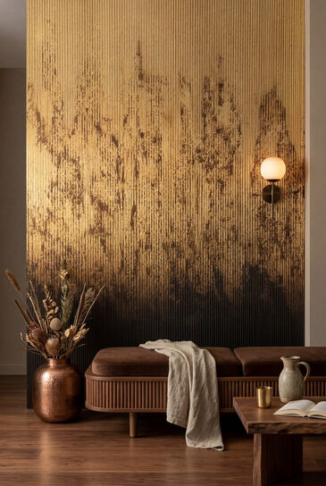 Living room with a golden-brown gradient wall design behind a low upholstered bench and a copper vase with dried flowers.