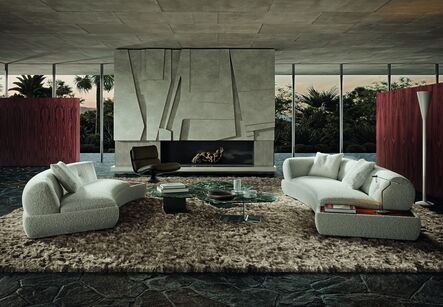 Two curved light-coloured sofas facing each other on a marble floor, with a sculpturally folded stone wall behind.