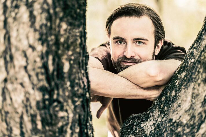 Der Pianist Daniil Trifonov sitzt in dunklem Anzug am Flügel, konzentriert über die Tasten gebeugt.