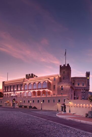 The Prince's Palace of Monaco with battlements and guardhouse in the evening light, the empty forecourt in front.
