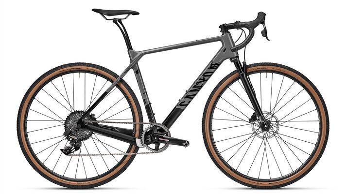 Gravel bike with a carbon frame, drop bars and wide knobbly tyres in side view on a light background.