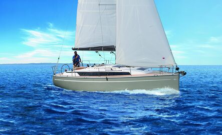 Segelyacht mit weißem Groß- und Vorsegel kreuzt bei klarem Wetter, im Cockpit steht ein Segler am Steuerrad.