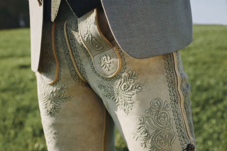 Close-up of cream-coloured lederhosen with floral embroidery and staghorn buttons on the side seam.