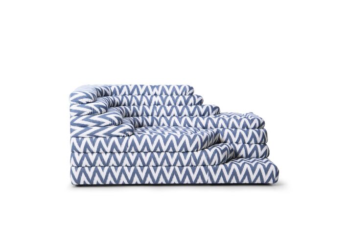 Freigestelltes Stufensofa mit blau-weiß gemustertem Outdoorbezug und lose aufgelegten Kissen.