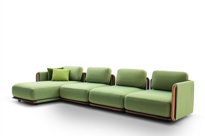 Large lounge with light-coloured upholstered furniture, side tables and a rug on a terrace, olive trees and wide hilly countryside behind.