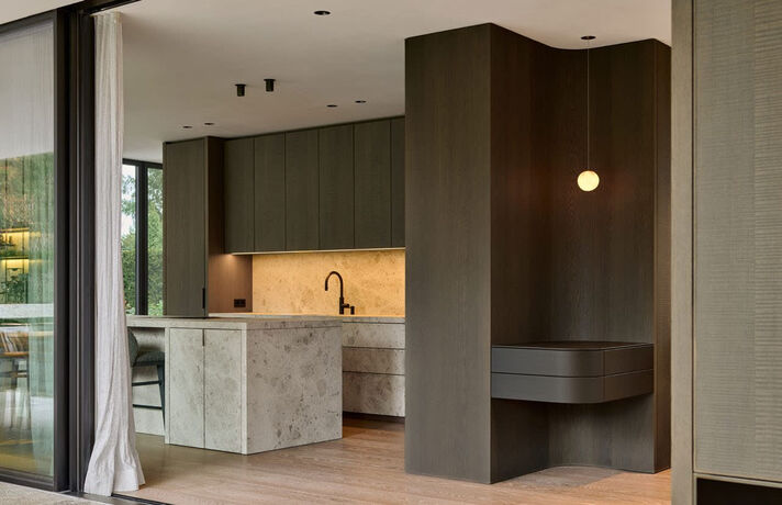 Open kitchen with a stone cooking island, wooden fronts and a floor-to-ceiling window front facing the garden.