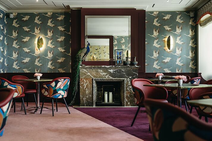 Gedeckte Tische im Goldenen Zimmer des Alois mit gemusterter Wandbespannung und Marmorkamin.