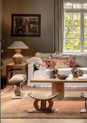 Hochwertig eingerichtetes Wohnzimmer mit Sprossenfenster, Kunstwerk an der Wand und Designermöbeln in einer Münchner Immobilie.